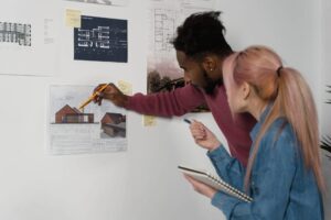 Couple looking at house blueprint on the wall.