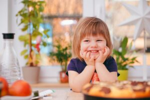 A young girl smiling widely in a kitchen