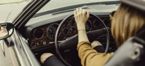 A woman driving with her hands on the steering wheel.