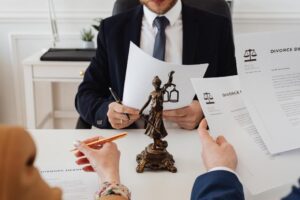 An image shows a man and woman looking through various divorce documents while a lawyer in a suit sits directly in front of them.