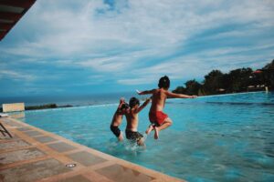  three kids jumping into a pool