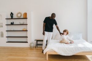  a man touching the back of a child who is sitting in a bed