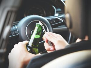 A man opening a beer while driving