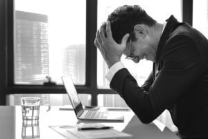 a man holding his head in front of a laptop