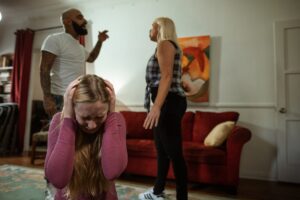 Couple arguing in front of their young daughter, who looks upset