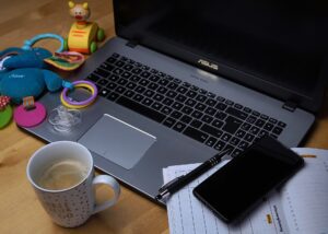 A laptop and planner next to kids’ toys