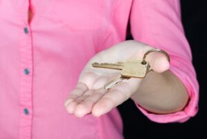 A person in a pink shirt holding out a key